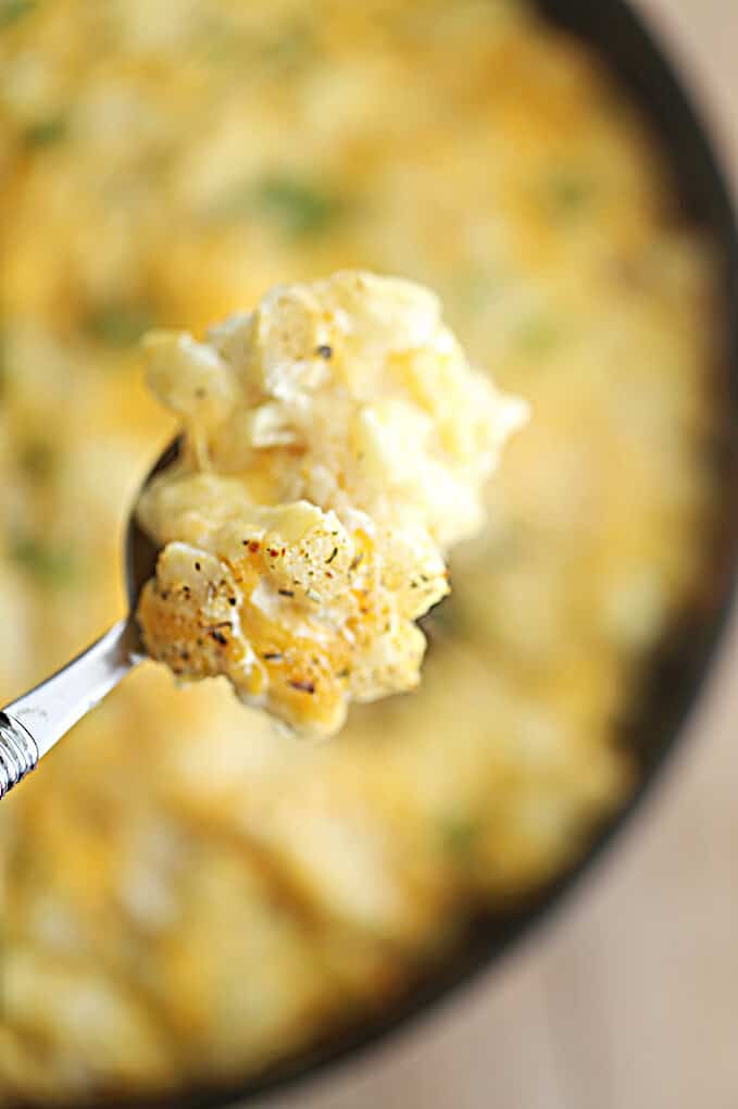 cast iron skillet with a scoop of this cheesy potato side dish