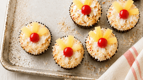 tray of pretty pineapple and coconut cupcakes with fruit on top createdbydiane