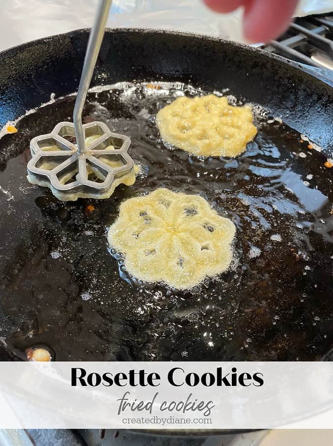 rosette iron cooking batter in a cast iron skillet for crispy lightweight cookies, then dust with powdered sugar