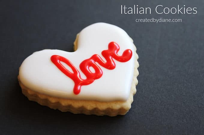 thick crinkle edge heart cookie with white frosting and red lettering LOVE