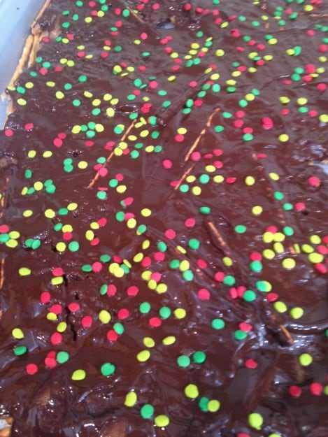 spreading chocolate and adding sprinkles to Christmas Crack