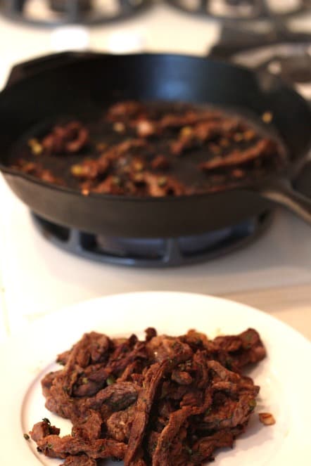 cooking carne asada in a cast iron skillet
