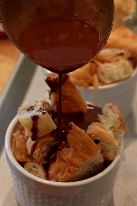 pouring chocolate pudding over croissants