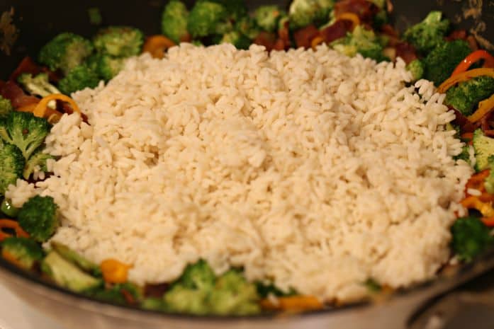 adding rice to vegetables for fried rice