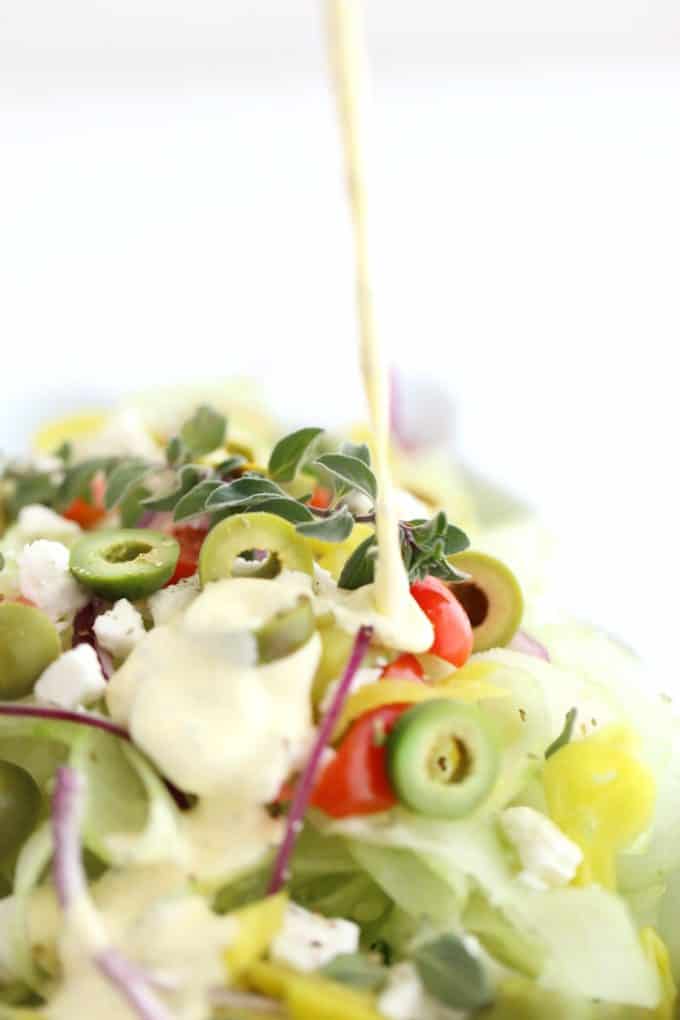 greek salad dressing drizzling onto salad www.createdbydiane.com