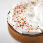 baked vanilla round cake with whipped cream and sprinkles