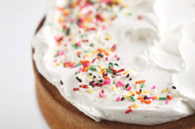 baked vanilla round cake with whipped cream and sprinkles