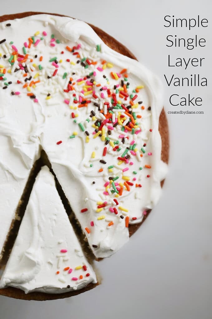 vanilla cake with whipped cream and rainbow sprinkles, sliced as if one piece is being removed from the cake
