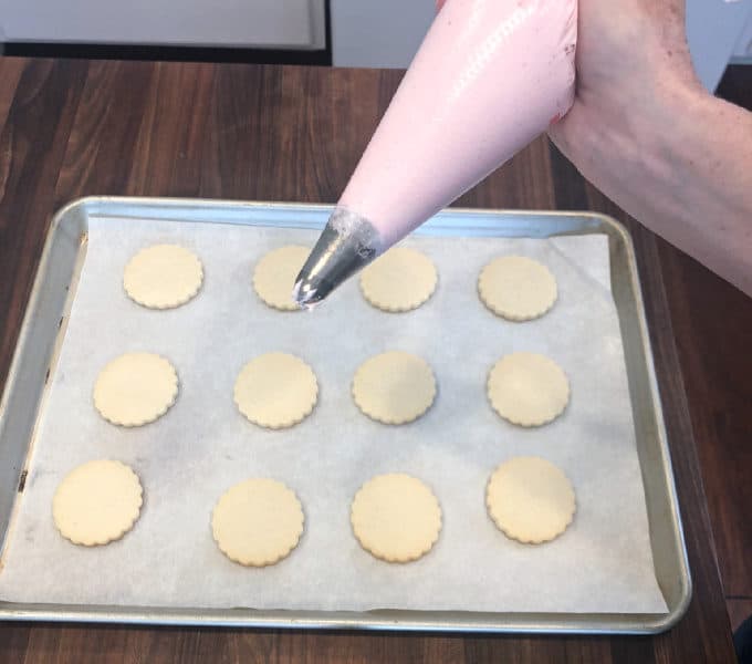 piping buttercream frosting onto sugar cookies www.createdbydiane.com