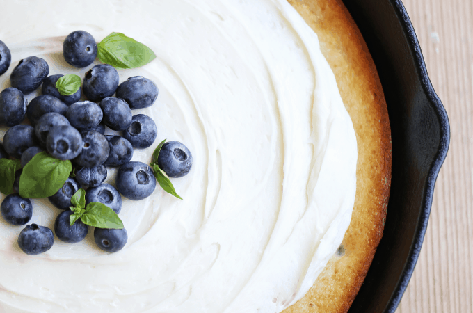 Banana Blueberry Cake in a skillet topped with cream cheese frosting createdbydiane.com