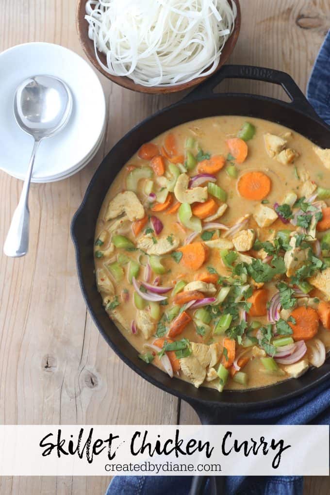 cast iron skillet with chicken, curry sauce, vegetables and rice noodles 