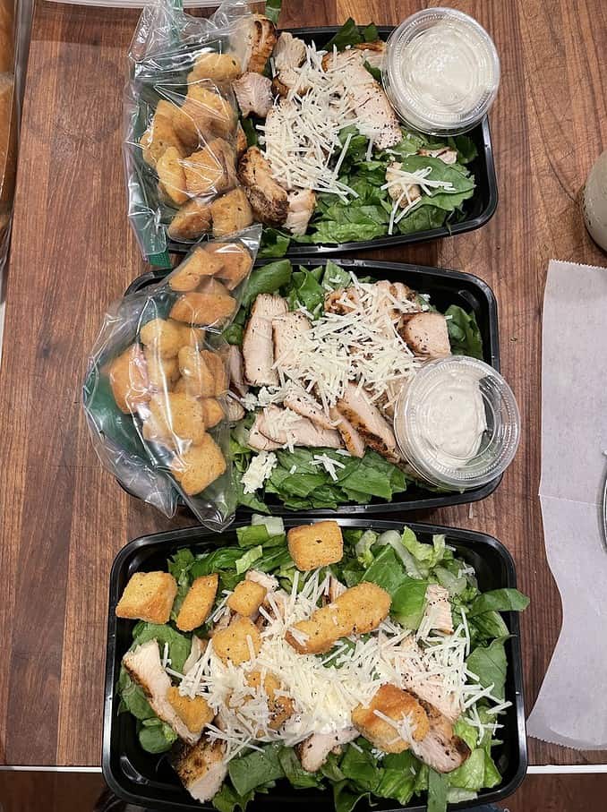 meal prep caesar salad with chicken in to-go containers with dressing in 2 oz cups