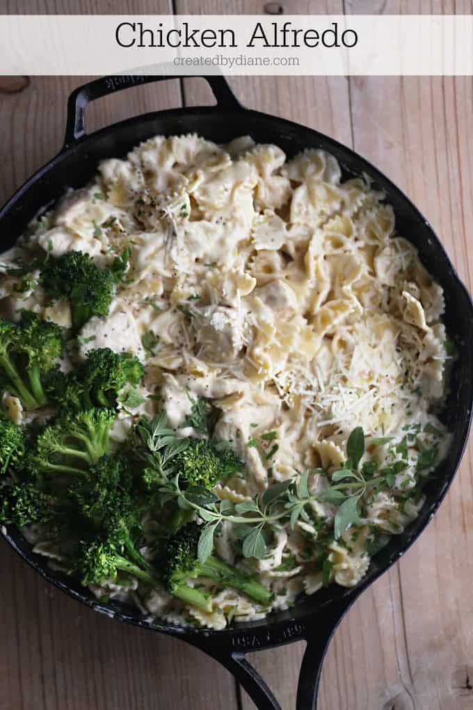 cast iron skillet loaded with chicken pasta and Alfredo sauce topped with broccoli
