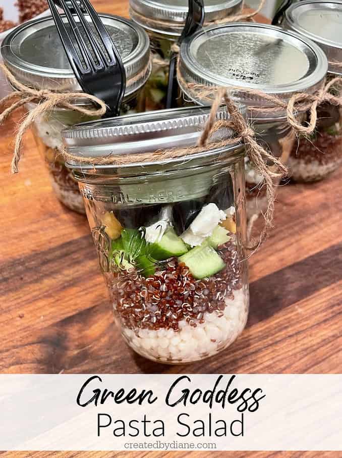 glass jars 16 oz with pasta, quinoa, feta, cucumber, olive, chicken peas and green goddess dressing with a plastic fork tied on for easy to-go meals