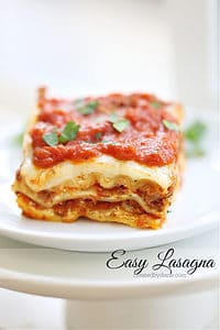 easy lasagna recipe, baked and sliced on a stack of white plates createdbydiane.com