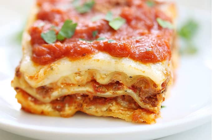 easy lasagna recipe, baked and sliced on a stack of white plates createdbydiane.com