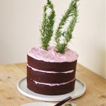 chocolate layer cake with lavender color and flavored frosting with rosemary tied to look like bunny ears on top of the cake
